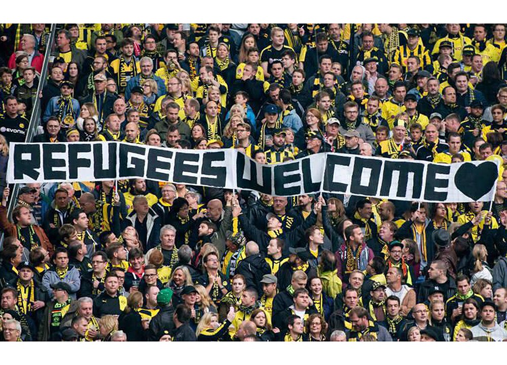 Torcida do Borussia Dortmund, da Alemanha, com faixa “Bem-vindos, refugiados”