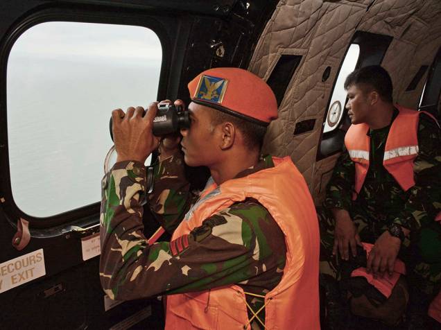 Soldado da Força Aérea da Indonésia usa um binóculo durante as operações de busca das vítimas do voo AirAsia QZ 8501 sobre o Mar de Java