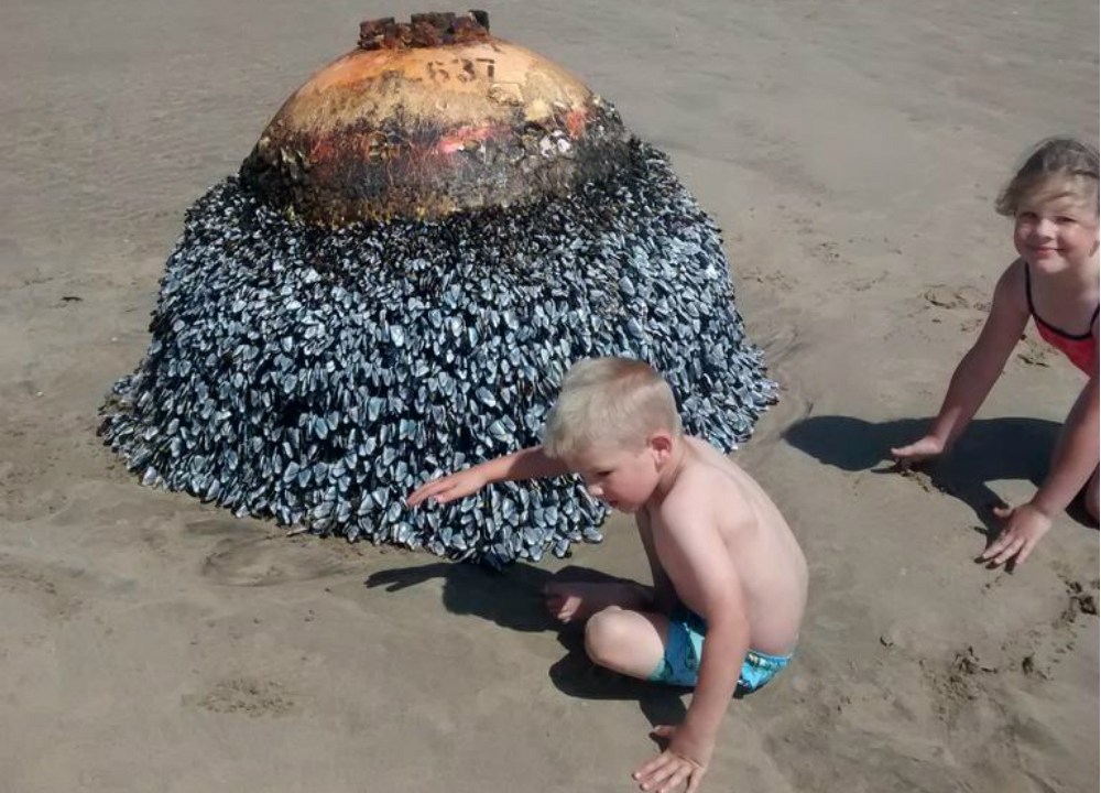 Duas crianças brincam inadvertidamente com uma bomba da II Guerra Mundial