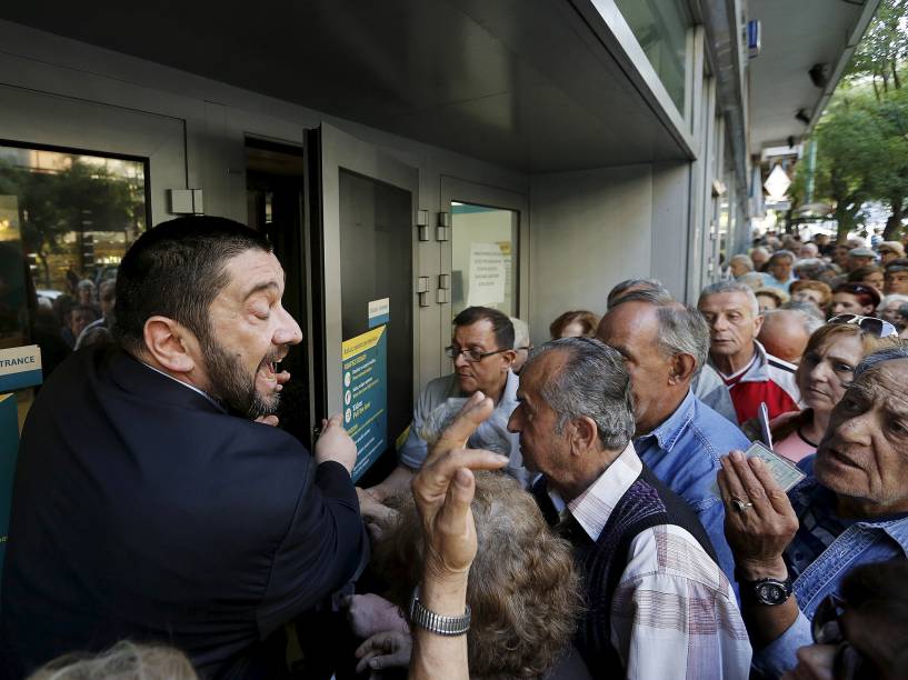 Gerente de banco tenta explicar a situação para centenas de aposentados que fazem fila em frente ao Banco Nacional para receber seus benefícios, em Atenas, Grécia