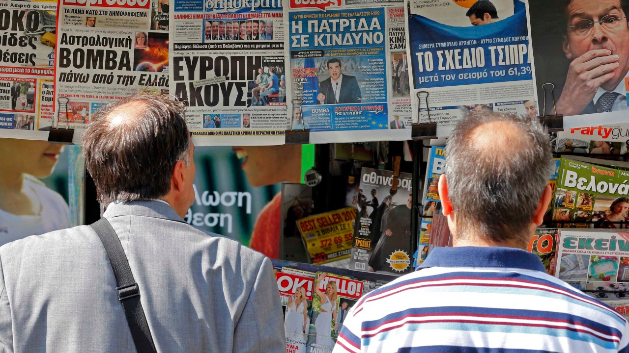 Pessoas olham para jornais com os resultados do referendo de domingo (6) em bancas no centro de Atenas, Grécia. Cerca de 61% dos gregos negaram as condições de resgate dos credotes em votação no domingo (5), deixando o futuro do país na zona do euro cada vez mais incerto