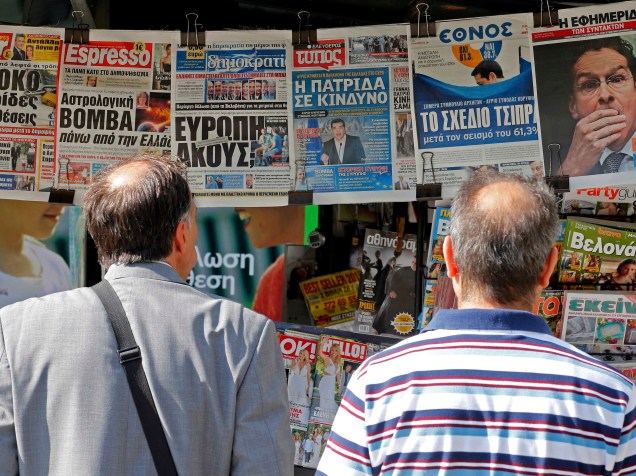 Pessoas olham para jornais com os resultados do referendo de domingo (6) em bancas no centro de Atenas, Grécia. Cerca de 61% dos gregos negaram as condições de resgate dos credotes em votação no domingo (5), deixando o futuro do país na zona do euro cada vez mais incerto