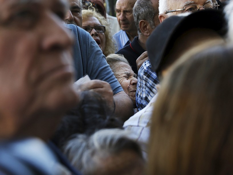Aposentados gregos aguardam na fila em agência bancária em Atenas nesta quarta-feira (1º) após governo permitir que eles façam saques acima de limite imposto