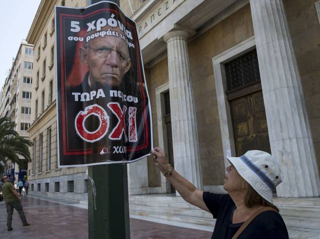 Mulher observa um pôster no centro da Grécia que mostra uma imagem do ministro das Finanças alemão, Wolfgang Schaeuble, com o slogan: Há cinco anos ele vem sugando seu sangue