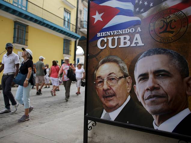 Turistas passam por imagem do Presidente americano Barack Obama e o Presidente cubano Raul Castro, com os dizerem "Bem-vindo a Cuba"
