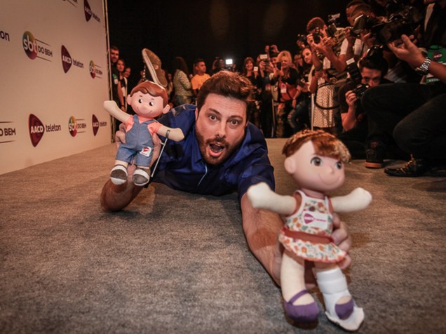 Danilo Gentili faz graça e se joga no chão com os bonecos Tonzinho e Nina durante o Teleton 2015 nos estúdios do SBT em São Paulo