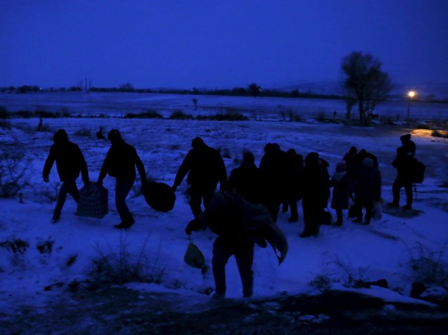 Imigrantes caminham por um campo coberto de neve depois de cruzar a fronteira da Macedônia, em Miratovac, na Sérvia