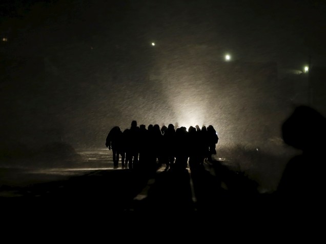 Imigrantes caminham por um campo coberto de neve depois de cruzar a fronteira da Macedônia, em Miratovac, na Sérvia