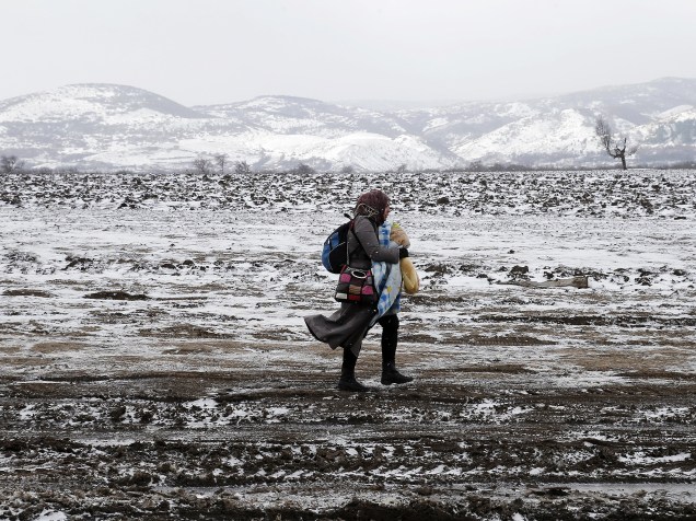 Uma refugiada caminha por um campo coberto de neve depois de cruzar a fronteira da Macedônia, em Miratovac, na Sérvia