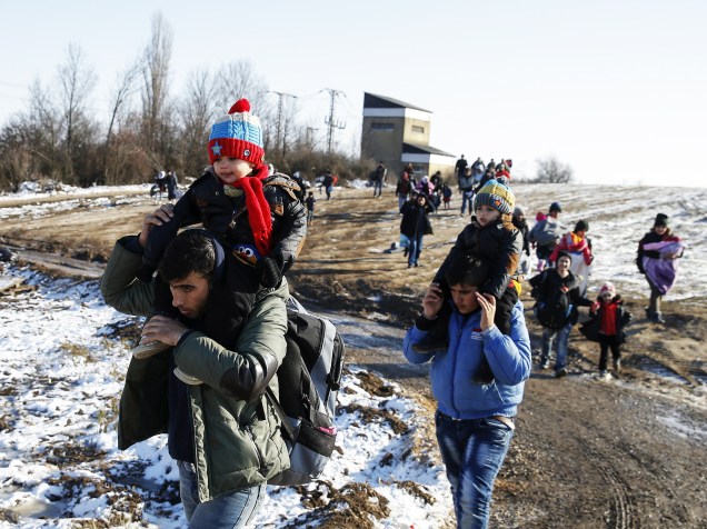 Imigrantes caminham por um campo coberto de neve depois de cruzar a fronteira da Macedônia, em Miratovac, na Sérvia