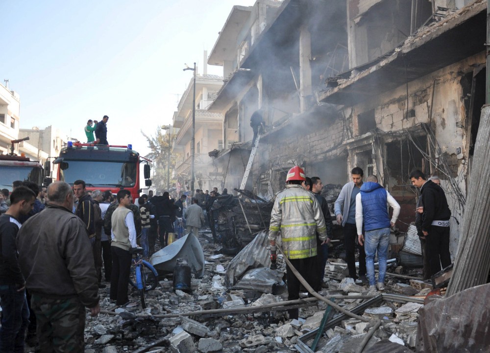 Equipes de resgate e civis no local onde aconteceram os atentados, em Homs