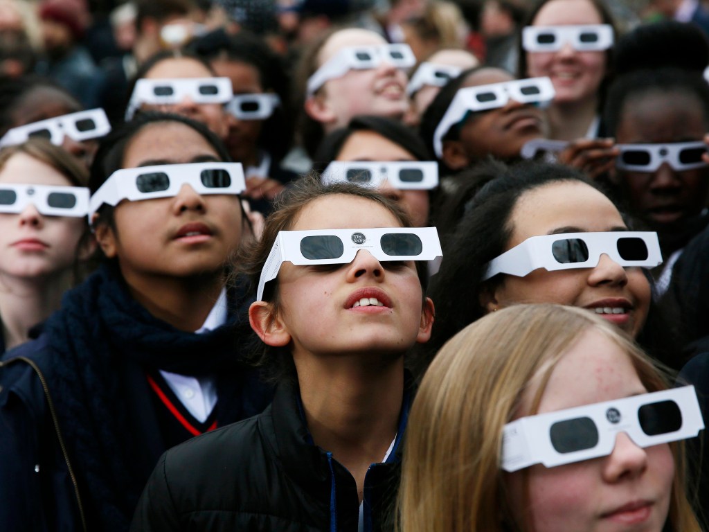 Crianças usam óculos para acompanhar o eclipse solar no Observatório Real de greenwich, em Londres