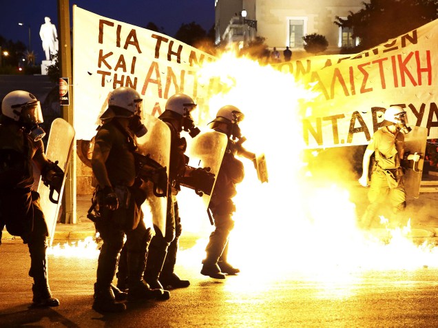 Polícia de choque fica entre as chamas das bombas de gasolina jogadas por um grupo de manifestantes em frente ao parlamento em Atenas, na Grécia - 15/07/2015