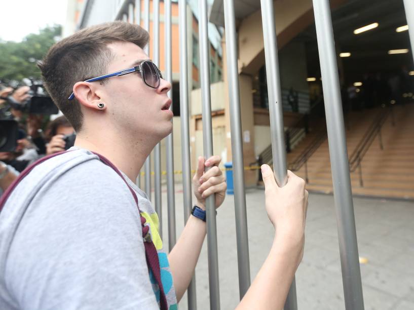 O estudante Lucas Prado, 23, tenta convencer os seguranças a abrir os portões após se atrasar no segundo dia de provas do Enem, no campus da Uninove, em São Paulo - 25/10/2015