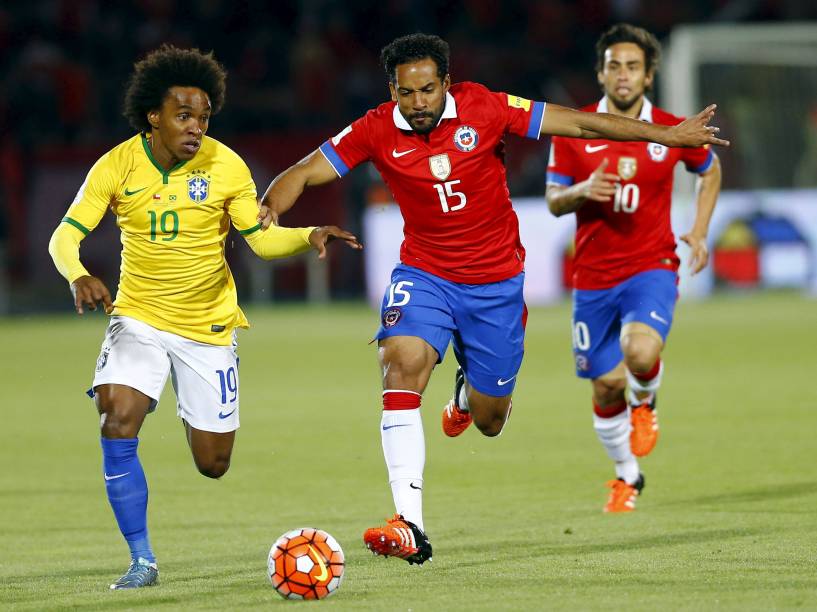 O meia William do Brasil controla a bola sob a marcação do volante Jean Beausejour do Chile