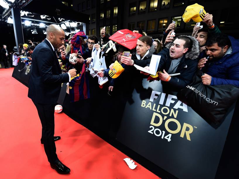 O francês Thierry Henry autografa pertences de fãs na entrada da Bola de Ouro, evento da FIFA em Zurique