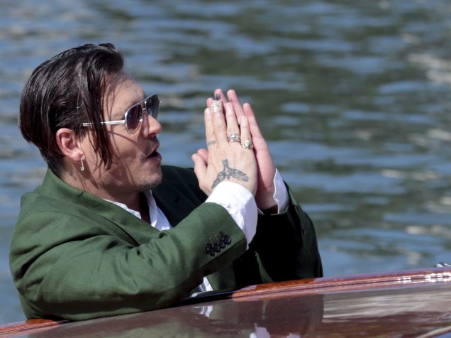 O ator Johnny Depp acena aos fãs ao deixar uma sessão de fotos do filme "Black Mess", no Festival de Veneza 2015