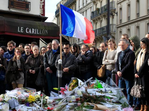 Pessoas fazem minuto de silêncio em homenagens às vítimas em frente ao restaurante Le Carillon, em Paris (França), nesta segunda-feira