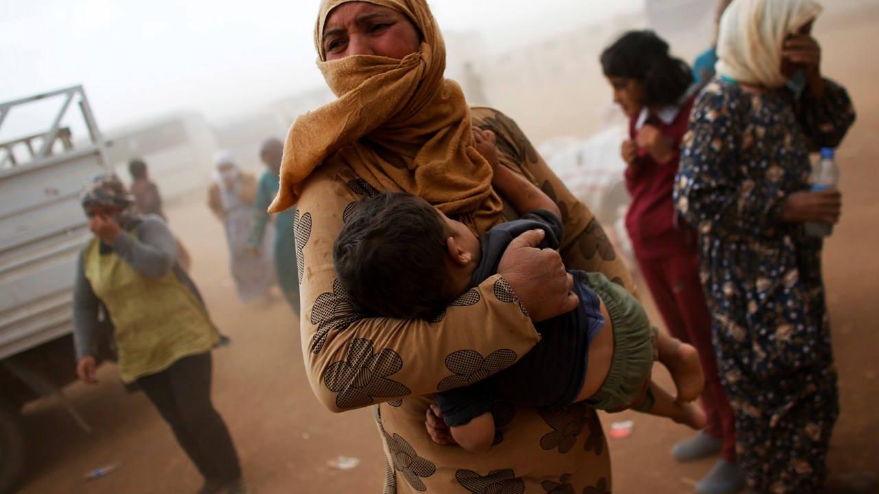 Refugiados curdos esperam por transporte durante uma tempestade de areia na fronteira turco-síria