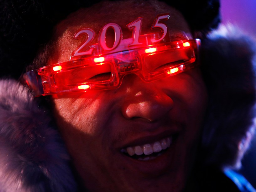 Chinês usa um par de óculos em forma do ano 2015 enquanto espera por um evento de contagem regressiva para comemorar a chegada do novo ano em frente ao Estádio Nacional, também conhecido como o Ninho de Pássaro, em Pequim