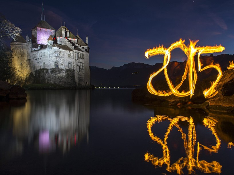 Homem escreve 2015 com fogo em homenagem ap no novo, em frente ao castelo Chateau de Chillon, no lago Genebra, em Veytaux, na Suíça 