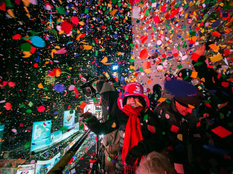 Turistas jogam confetes e papeis cortados de um hotel na Times Square para comemorar a virada do ano novo em Nova York