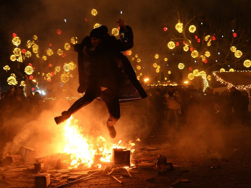 Homem pula uma fogueira para celebrar a chegada do ano novo na praça Vorosmarty, em Budapeste, Hungria