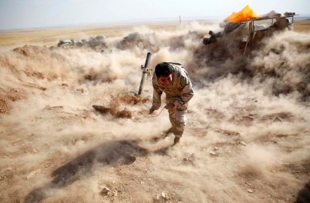 Combatente curdo Peshmerga lança morteiro em direção a cidade de Zummar, controlada pelo Estado Islâmico, no Iraque