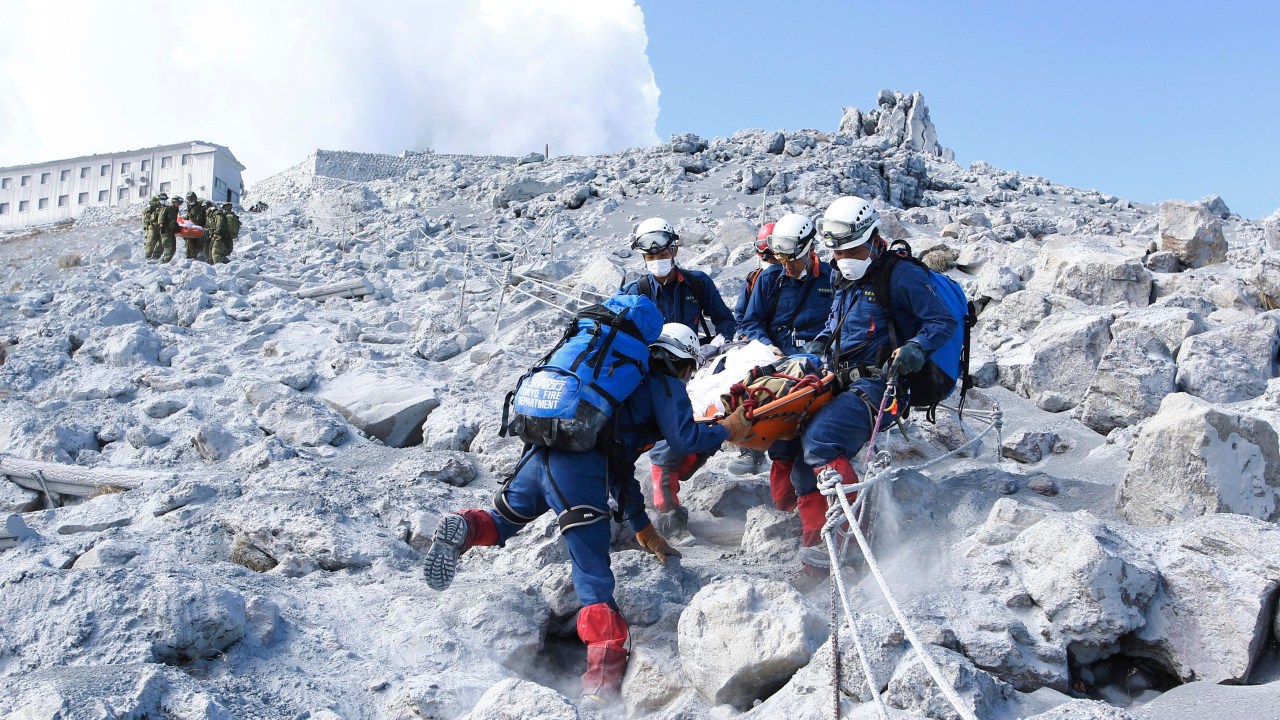 Bombeiros carregam vítima soterrada por uma eripção vulcânica, durante uma operação de resgate perto do pico do Monte Ontake, região central do Japão