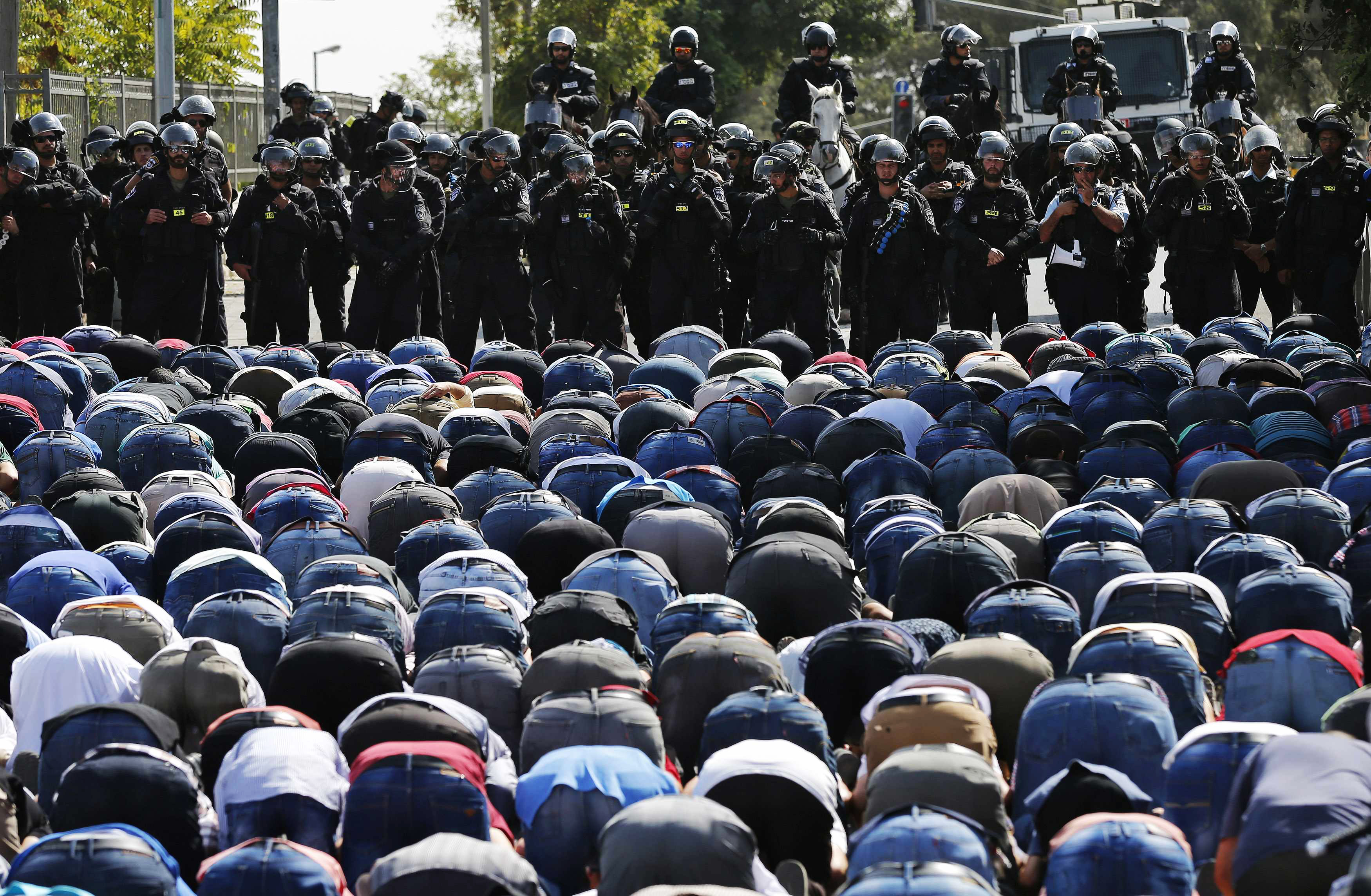 Palestinos rezam enquanto policiais israelenses tomam guarda, no leste de Jerusalém