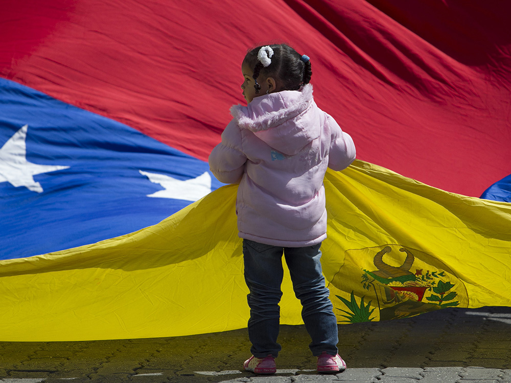 Garota é vista segurando a bandeira nacional da Venezuela, em Caracas. Centenas de pessoas protestaram nesta segunda-feira (01) em frente ao consulado da Colômbia para que o governo de Bogotá responda a solicitação do país de extraditar Leiver Padilla, suspeito do assassinato do deputado Robert Serra