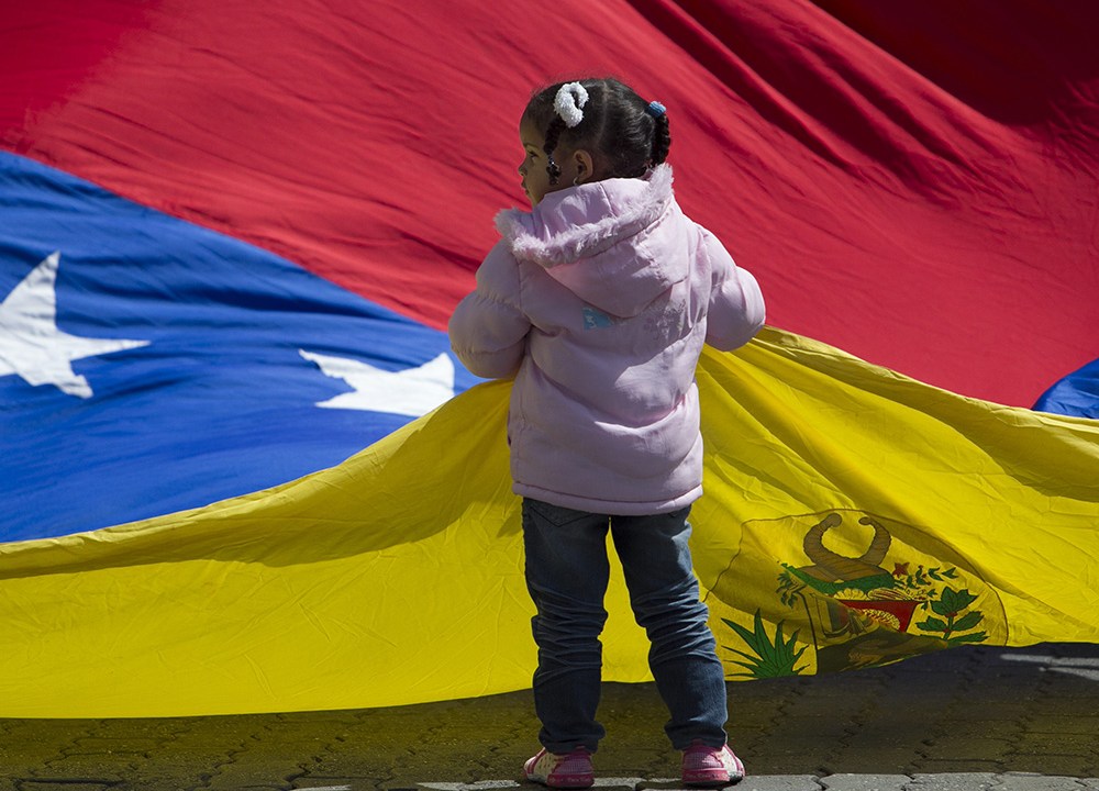 Garota é vista segurando a bandeira nacional da Venezuela, em Caracas. Centenas de pessoas protestaram nesta segunda-feira (01) em frente ao consulado da Colômbia para que o governo de Bogotá responda a solicitação do país de extraditar Leiver Padilla, suspeito do assassinato do deputado Robert Serra