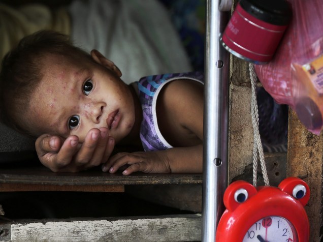 Criança descansa no colo da mãe em sua cabana enquanto espera para serem evacuados de uma favela de Baseco, em Manila, nas Filipinas em decorrência da chegada do super tufão Hagupit - 05/12/2014