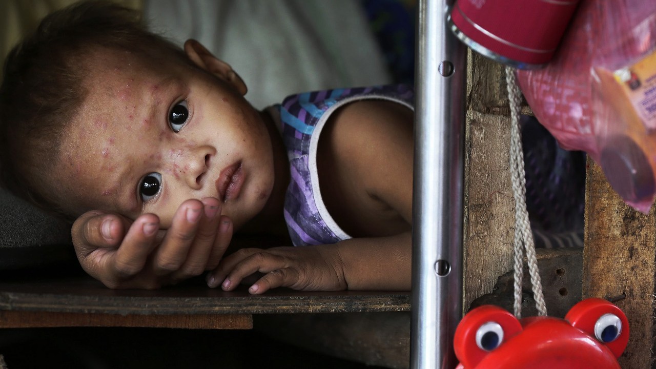 Criança descansa no colo da mãe em sua cabana enquanto espera para serem evacuados de uma favela de Baseco, em Manila, nas Filipinas em decorrência da chegada do super tufão Hagupit