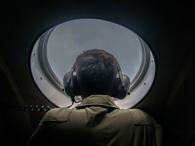 Membro das forças armadas da Indonésia olha da janela de uma aeronave durante operação de busca e salvamento do voo QZ8501 da AirAsia, sobre as águas do mar de Java - 29/12/2014