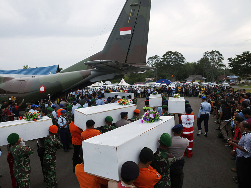 Caixões contendo os restos mortais dos passageiros do AirAsia QZ8501 recuperados do mar são transportados para um avião militar antes de serem levados a Surabaya, onde o voo teve origem, no aeroporto de Pangkalan Bun, Indonésia
