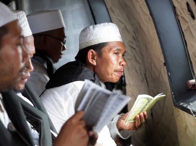 Clérigo muçulmano faz uma pausa enquanto ele lê versos do Alcorão durante uma oração para as vítimas do voo AirAsia QZ8501, dentro de um helicóptero da Força Aérea da Indonésia que sobrevoa o mar de Java em busca de vítimas e partes da aeronave - 06/01/2015
