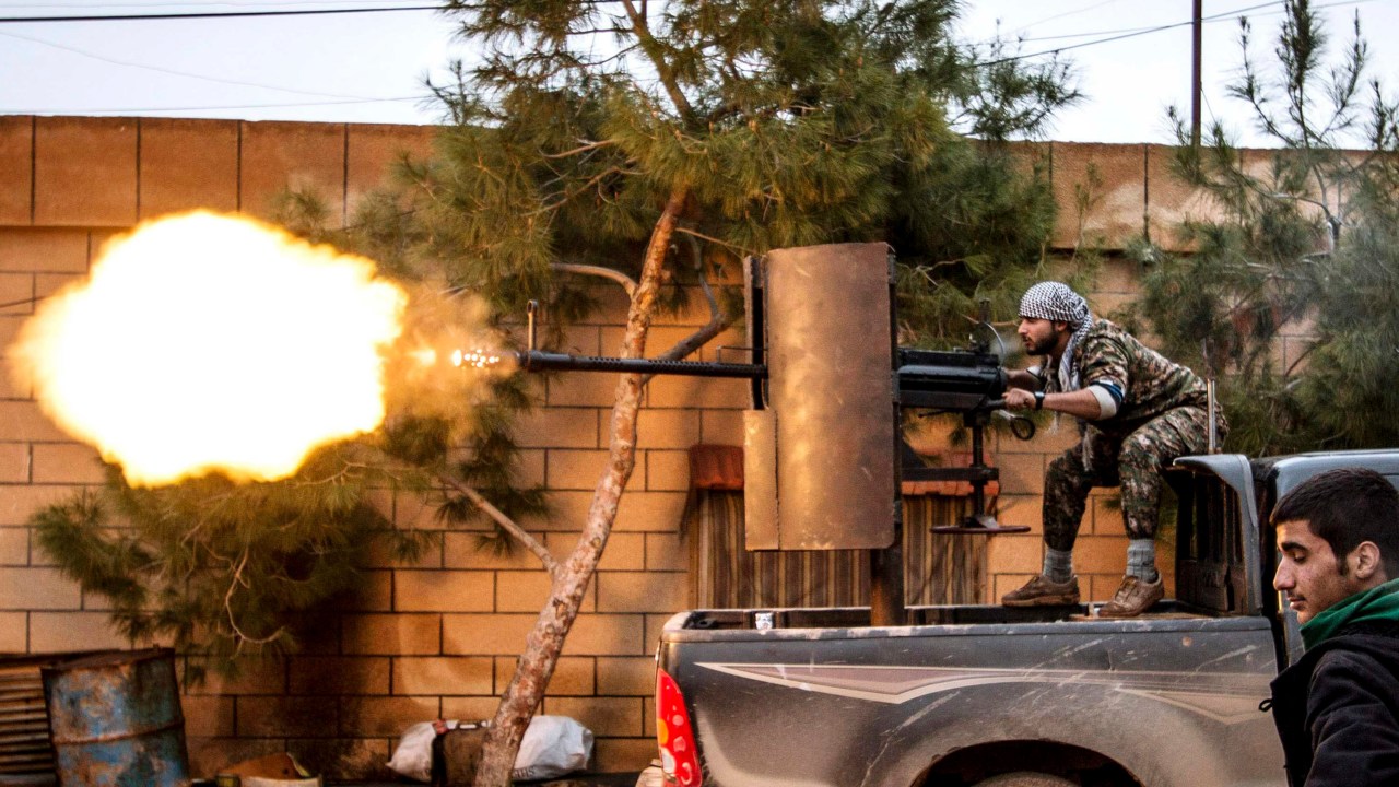 Membro da milícia curda Unidades de Proteção Popular (YPG) dispara uma arma anti-aérea da aldeia de Tel Tawil na direção de combatentes do Estado Islâmico posicionados na zona rural da cidade de Tel Tamr, na Síria - 25/02/2015
