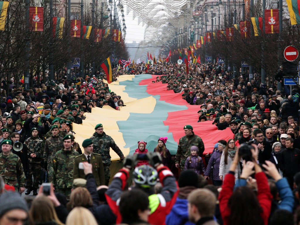 Lituânios caminham com uma bandeira nacional gigante durante cerimônia do 25º aniversario de independência em relação à União Soviética, na cidade de Vilnius, Lituânia