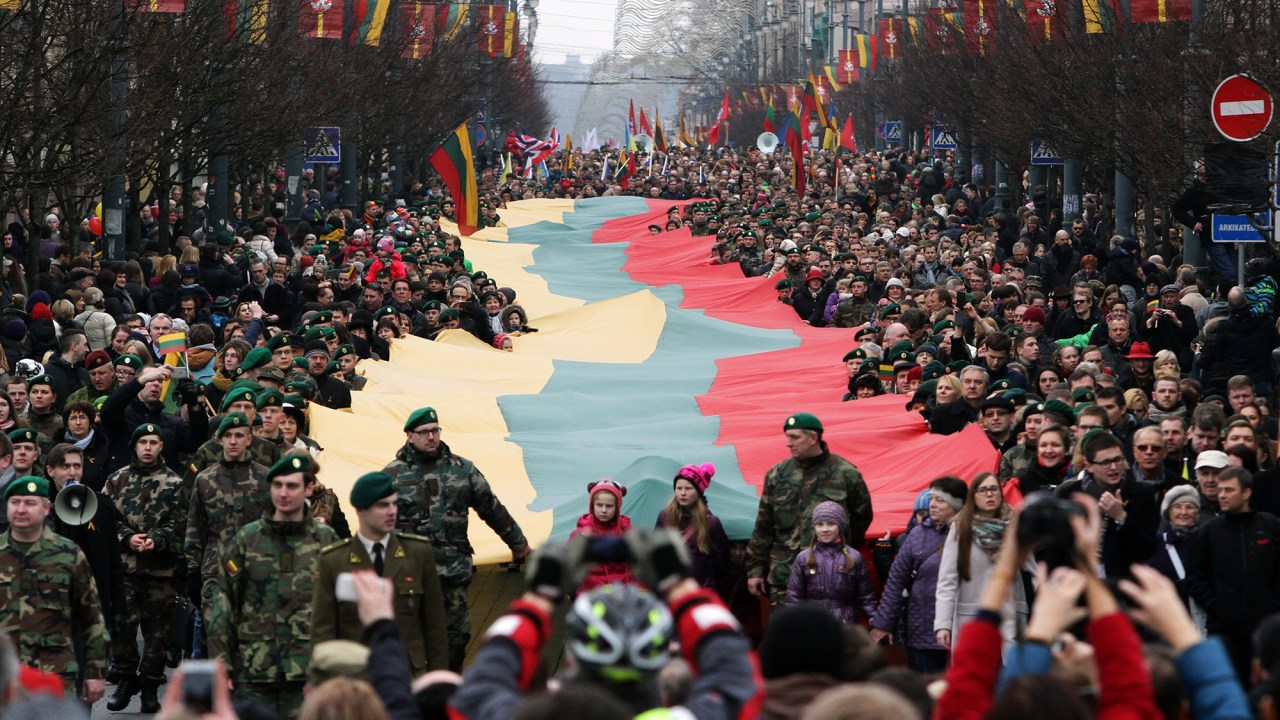 Lituânios caminham com uma bandeira nacional gigante durante cerimônia do 25º aniversario de independência em relação à União Soviética, na cidade de Vilnius, Lituânia