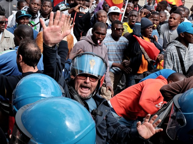 Agente da polícia gesticula durante uma manifestação de imigrantes em busca de asilo em Roma, na Itália