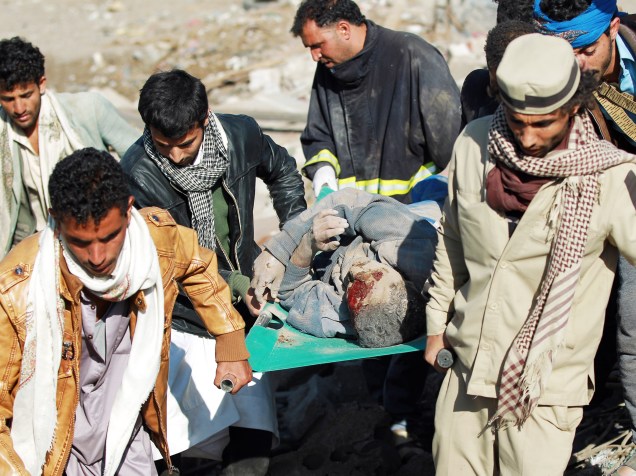 Homens carregam um ferido após retirá-lo dos escombros de uma casa destruída por bombardeio perto do aeroporto de Sana, no Iêmen - 26/03/2015