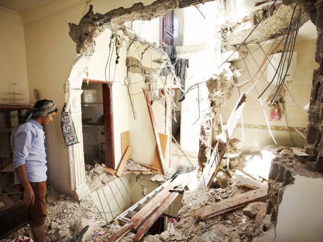 Homem observa os danos causados em sua casa após ataque aéreo em Sanaa, no Iêmen - 20/04/2015