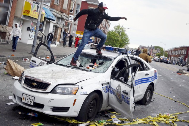 Manifestante sobe em um carro de polícia durante confrontos em Baltimore, EUA - 27/04/2015