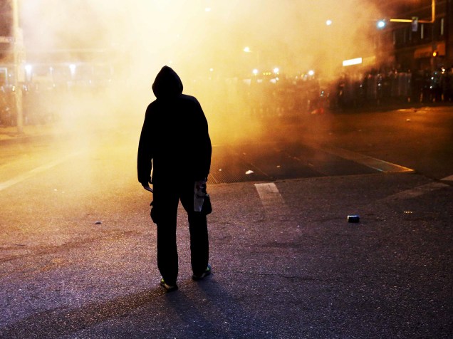 Manifestante caminha entre uma nuvem de fumaça durante confrontos com a polícia em Baltimore (EUA)