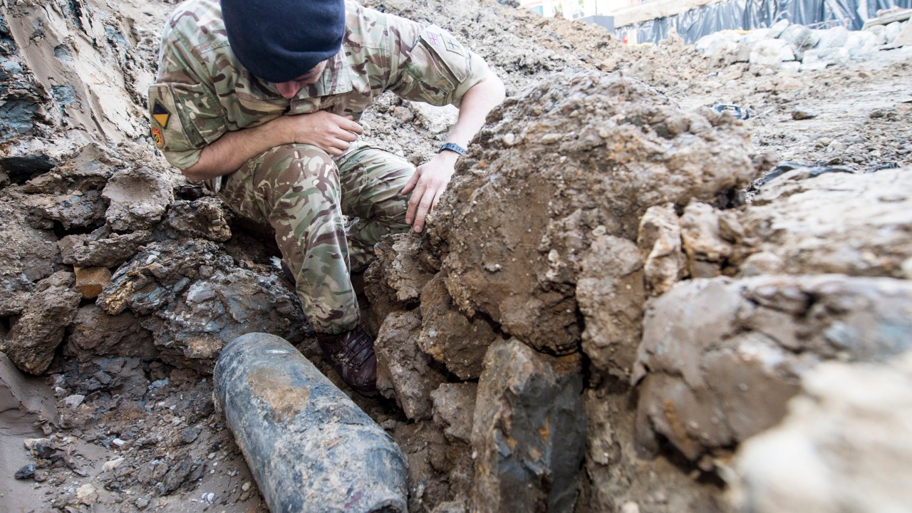 Expert em desarmamento de explosivos inspeciona uma bomba da Segunda Guerra Mundial que foi desenterrada de um bairro residencial em Londres