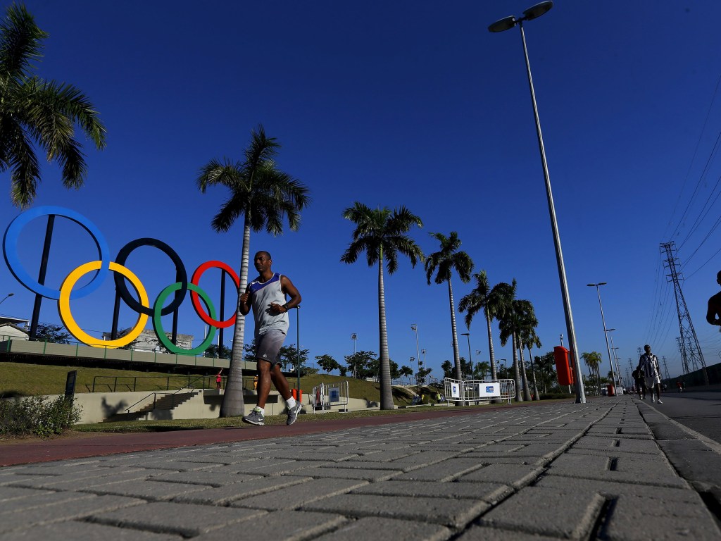 Homem corre pelo Parque da Madureira ao lado do símbolos das Olímpiadas Rio 2016, no Rio de Janeiro