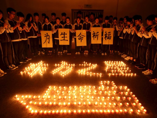 Estudantes fazem orações por passageiros de cruzeiro. Equipes de mergulhadores procuram cerca de 400 pessoas desaparecidas no naufrágio no rio Yang Tsé, na China. Em chinês, lê-se "Reze pela vida" - 03/06/2015