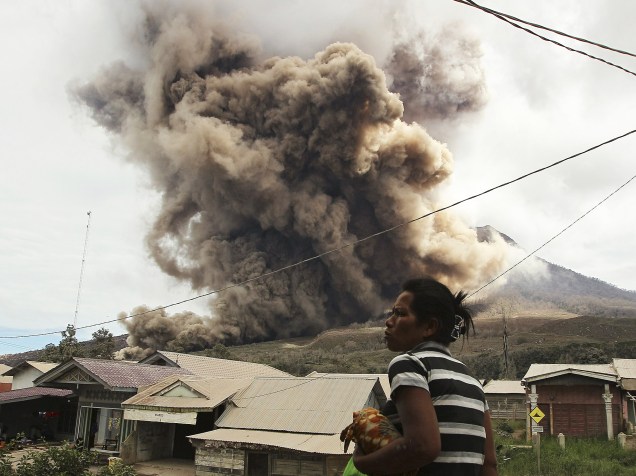 <p>Mulher observa erupção do vulcão do Monte Sinabung, em Tiga Kicat, região norte da Indonésia. Sinabung está entre os 130 vulcões ativos no país e está em atividade desde de 2010, depois de permanecer adormecido por 400 anos</p>