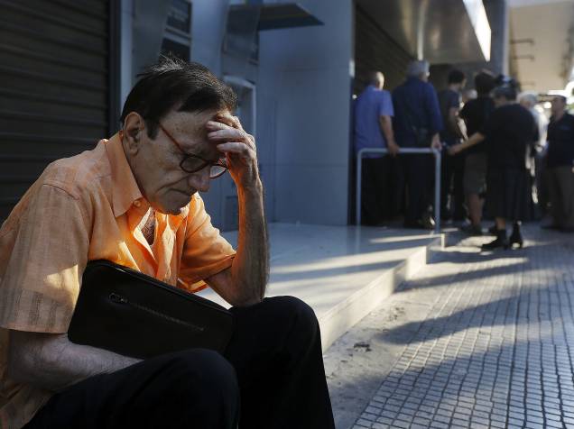 Giorgos, um aposentado de 77 anos, fica fora de uma sucursal do Banco Nacional da Grécia em Atenas, enquanto espera, juntamente com dezenas de outros pensionistas, na esperança de obter seus benefícios - 29/06/2015